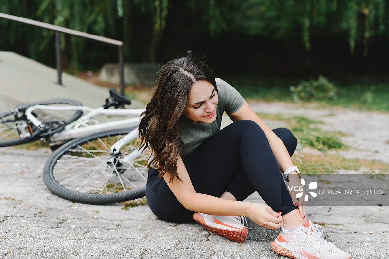 自行车事故后坐在地上难受地检查脚踝的女骑手图片素材