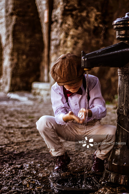 复古风格的摄影，男孩在森林中的喷泉喝水图片素材
