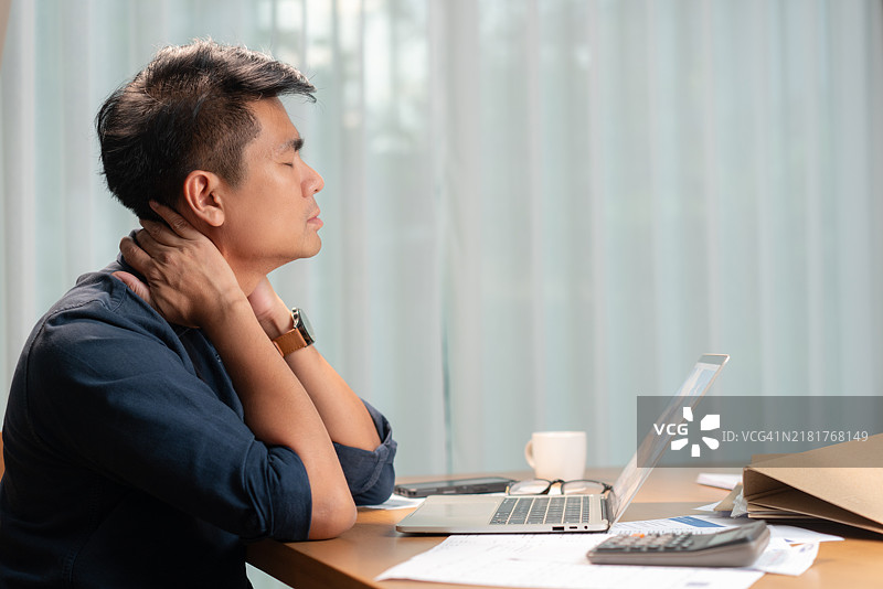 男人在办公桌工作时颈部疼痛图片素材