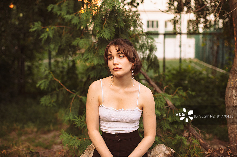 坐在树干上的沉思年轻女性肖像图片素材