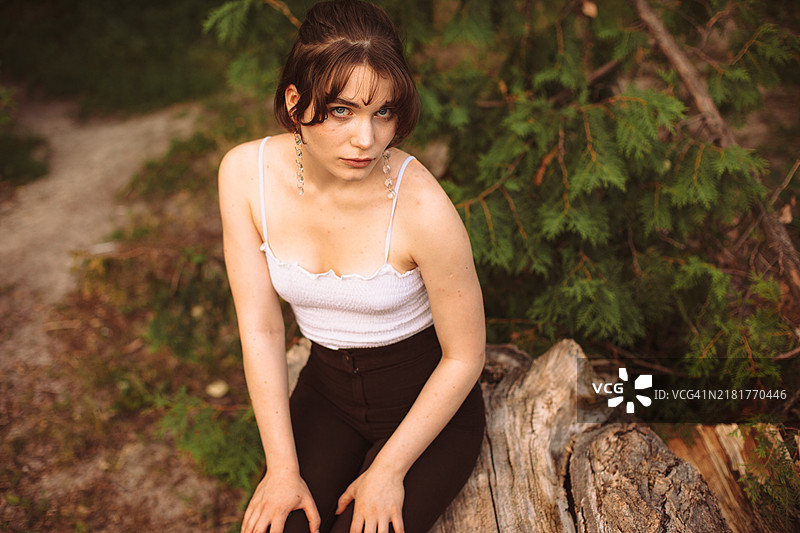 坐在树干上的美丽年轻女性肖像图片素材