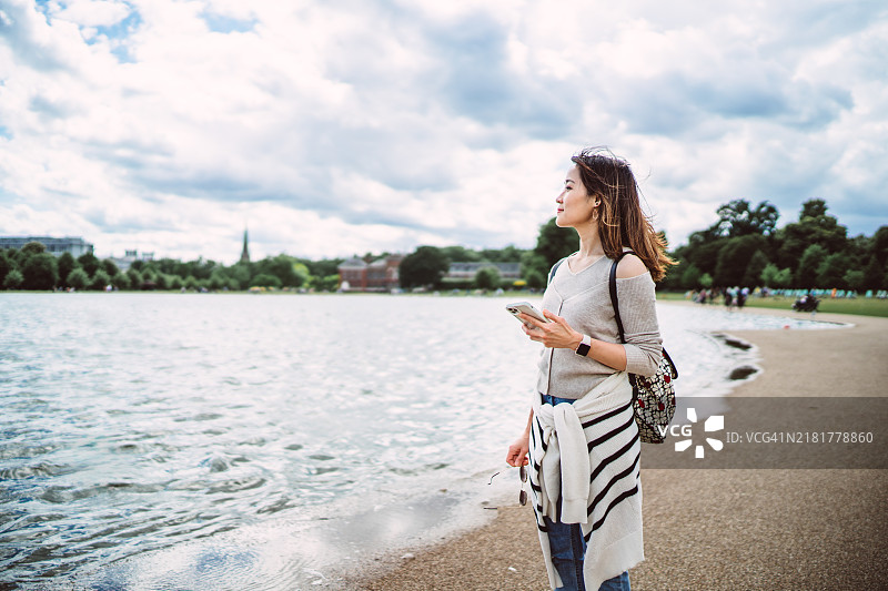 女人在湖边享受大自然时使用智能手机图片素材