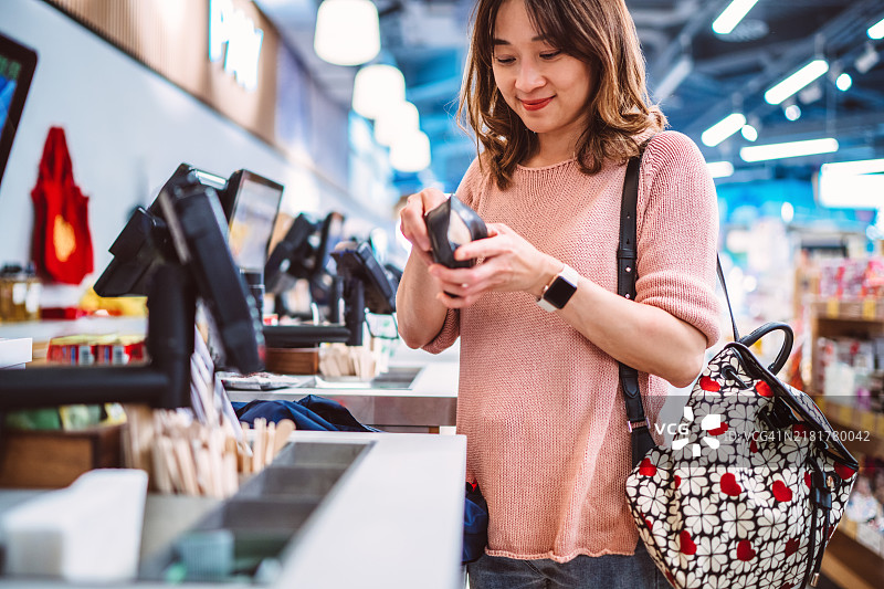 快乐的亚洲女性在超市自助结账台付款图片素材