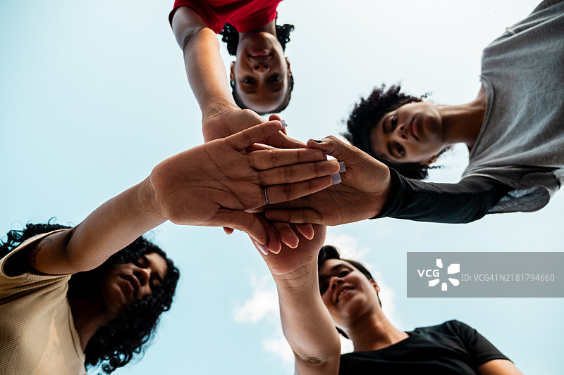 年轻女运动员在运动场上叠手。图片素材