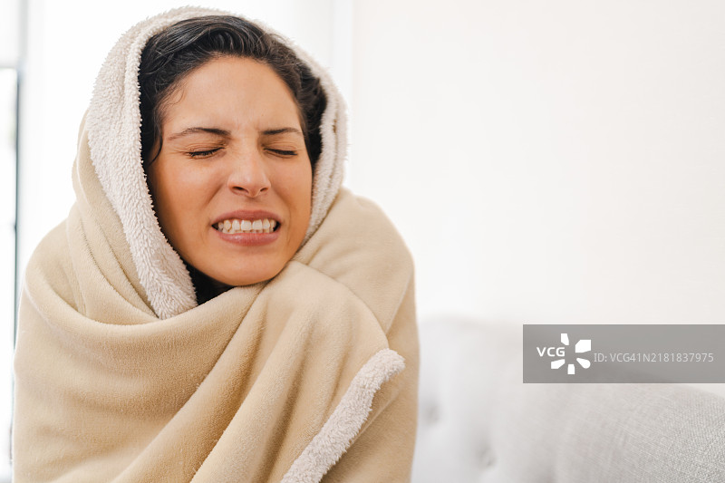 裹着毯子的寒冷女性坐在沙发上图片素材