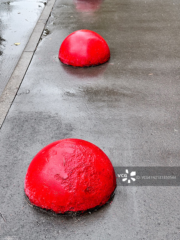 红色混凝土半球体放置在沥青上以防止非法停车图片素材