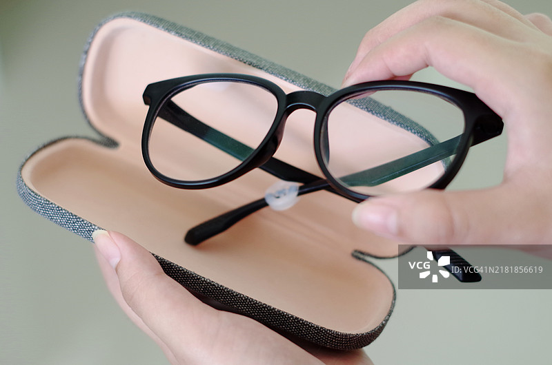 手持黑色塑料眼镜盒图片素材