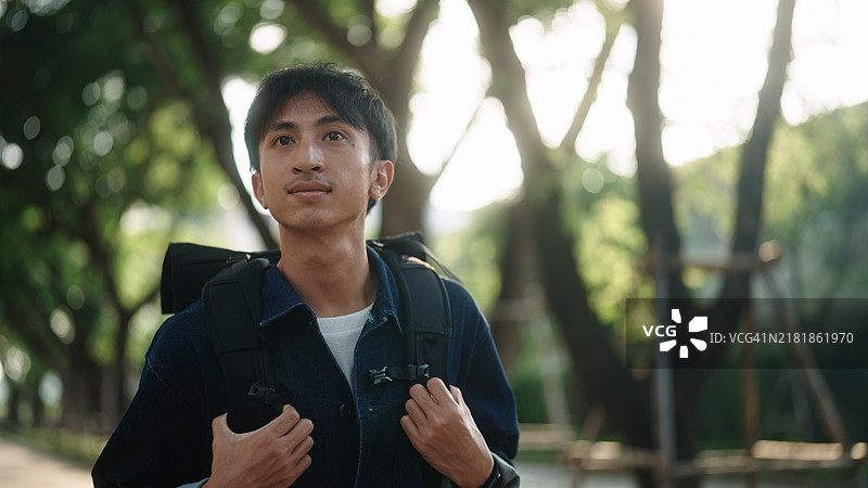 亚洲男人在绿色环境中行走图片素材