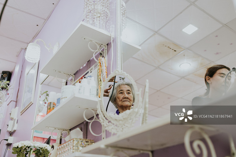 一位老年女性正在接受专家的美容护理。图片素材