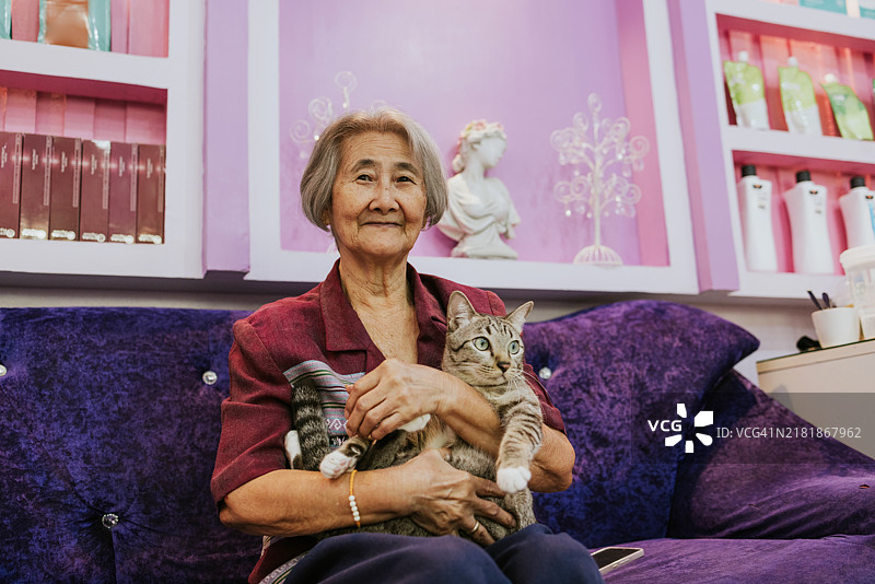 老年女性美容院与她的宠物猫的肖像。图片素材
