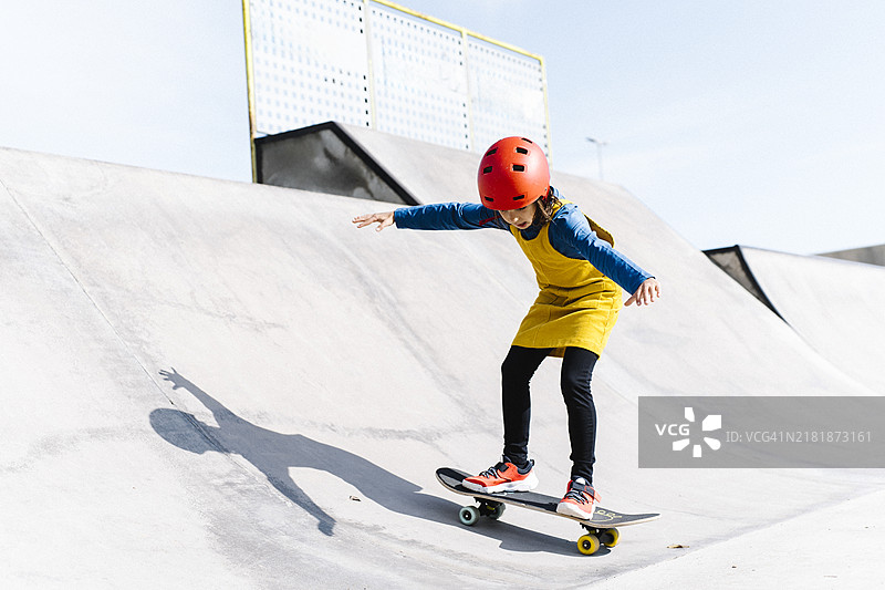 在滑板公园戴着头盔玩滑板的年轻女孩图片素材