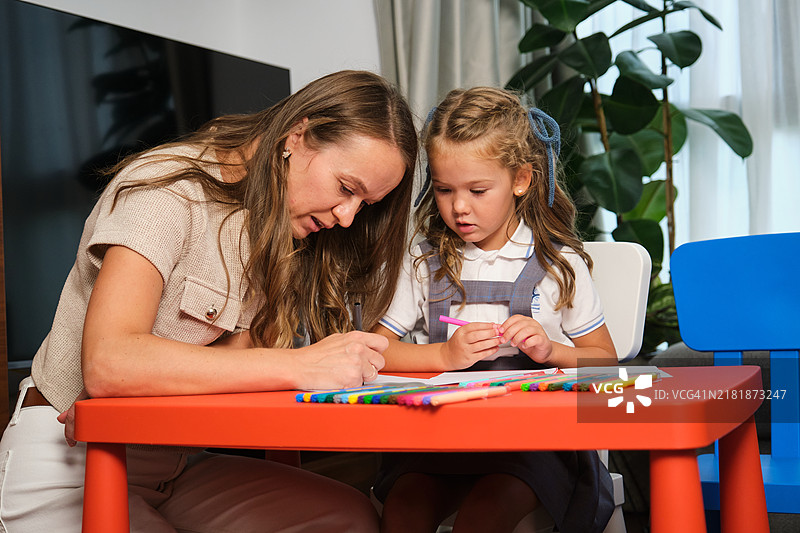 母亲在家里帮助女儿做作业，一起画画图片素材