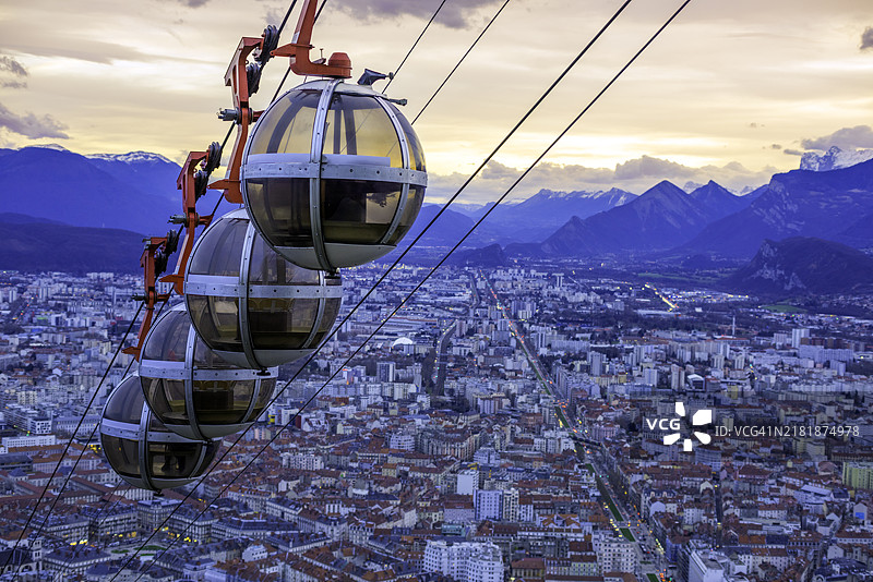 格勒诺布尔-巴士底缆车在黄昏时分到达山顶，城市在背景中。图片素材