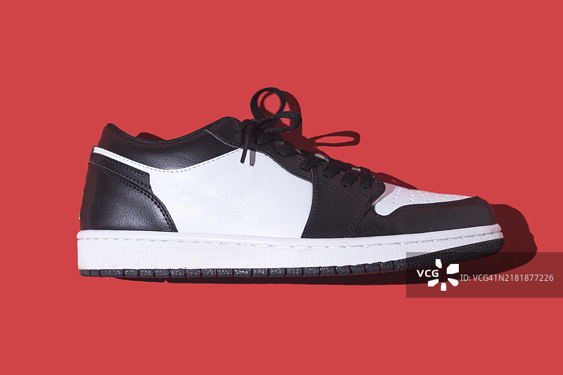 红色背景上的黑白篮球鞋：运动鞋、篮球、复古、时尚、收藏和休闲概念图片素材