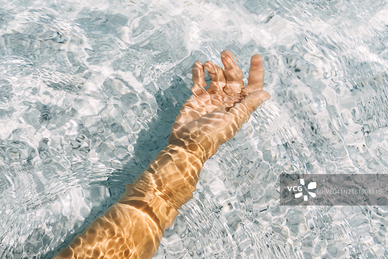 清澈的水中，阳光照耀在女人手上图片素材