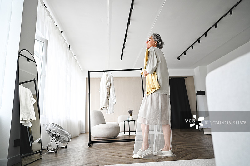 一位老年女性在镜子前准备。图片素材