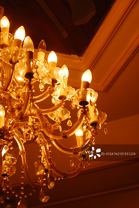 一盏古董吊灯优雅地悬挂着，散发出温暖的光芒，凭借其精致的水晶创造出闪耀的永恒优雅展示。图片素材