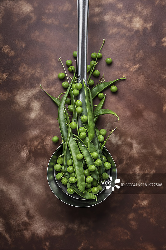 新鲜生豌豆放在厨房的勺子里，背景为斑驳的棕色。图片素材