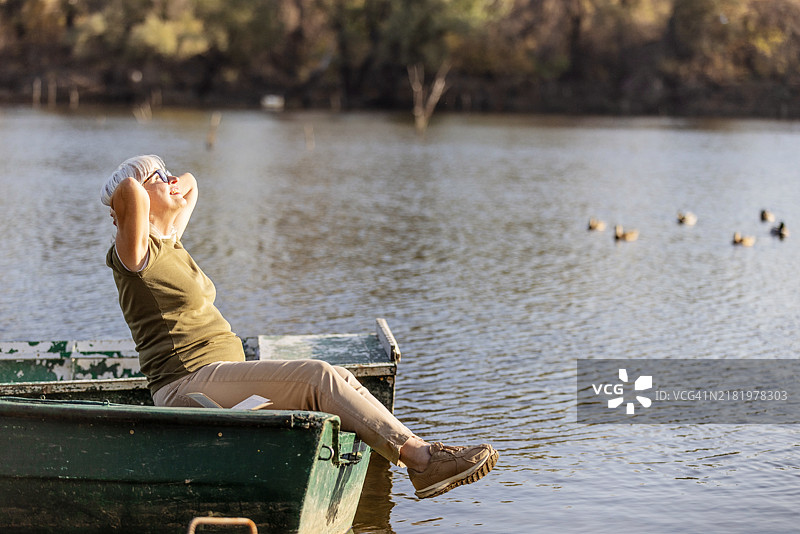 安静湖泊环境中放松的老年女性在船上图片素材