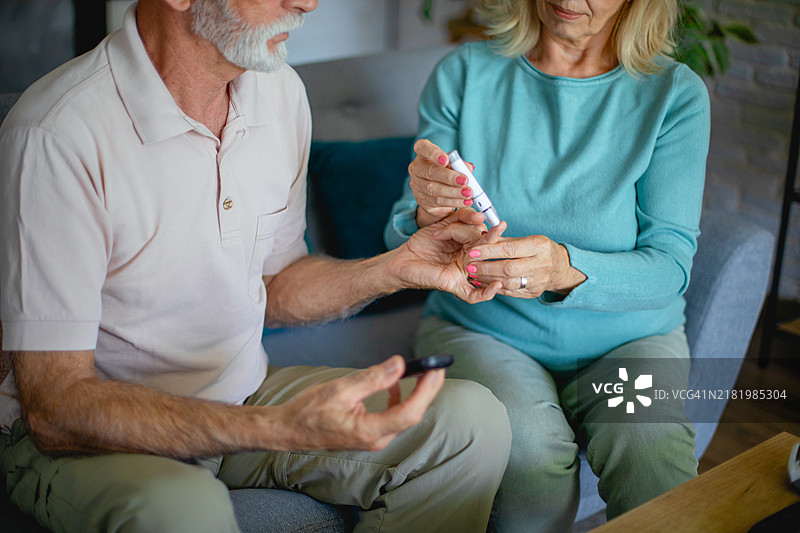 老年夫妇用刺血针在手指上检查血糖水平图片素材