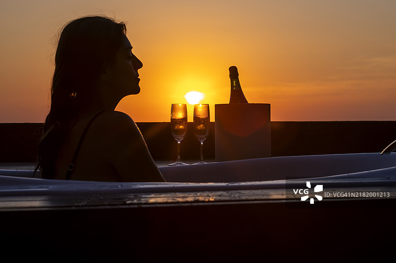 女人在日落时享受一杯葡萄酒图片素材