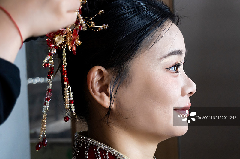 一位穿着传统服饰的亚洲女性正在修整妆容。图片素材