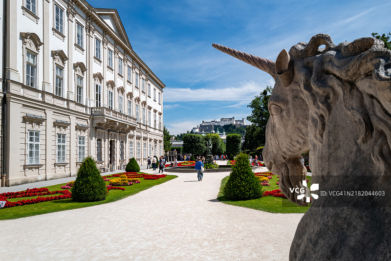游客在萨尔茨堡的米拉贝尔花园中走过独角兽雕像和花坛。图片素材