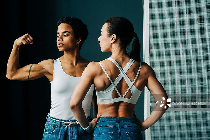 强壮而肌肉发达的女性展示她们的肱二头肌。图片素材