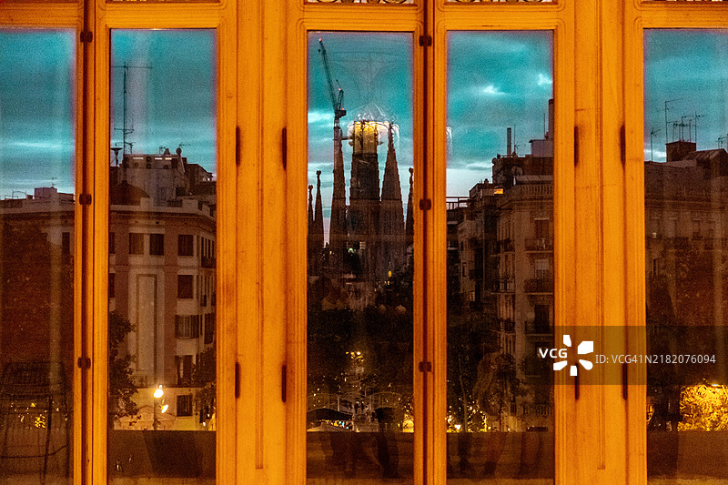 在巴塞罗那黄昏时分通过窗户拍摄圣家堂的剪影图片素材