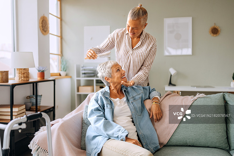 微笑的女人在家里帮助她的母亲梳头发图片素材