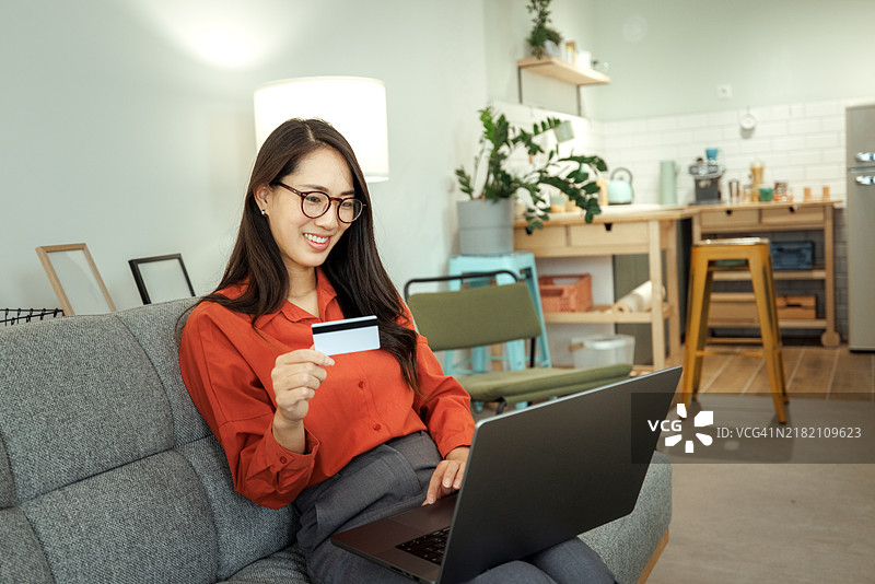 微笑的女性在家中使用笔记本电脑进行在线购物图片素材