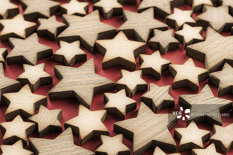 红色背景上密集排列着不同大小的木质圣诞星星背景图案图片素材