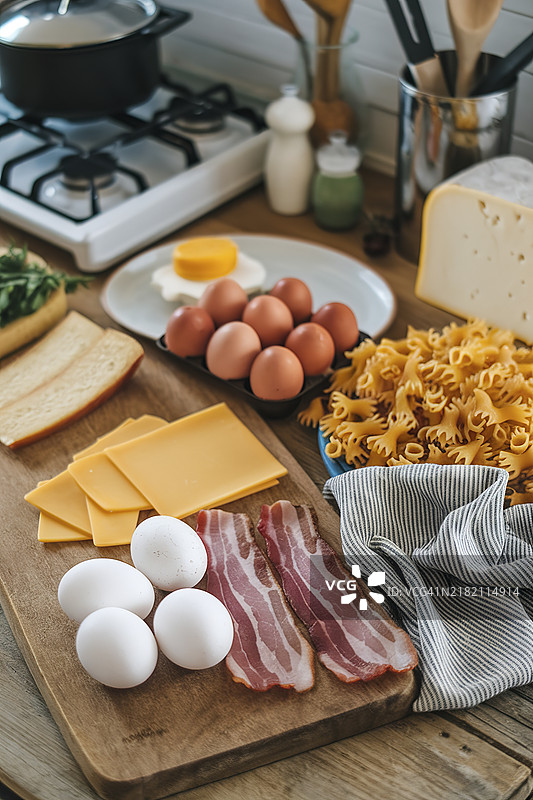 一张木桌上摆放着各种烹饪食材，包括鸡蛋、培根、奶酪和意大利面。图片素材