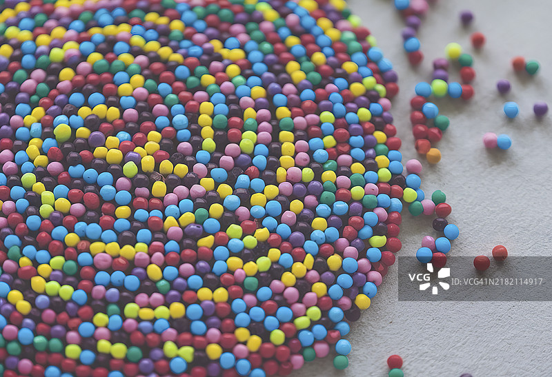 一组生动多彩的小圆形多色珠子或糖屑在特写视图中散落开来图片素材