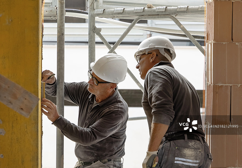 两位工匠正在使用水平旋转激光水平仪进行施工或翻新图片素材