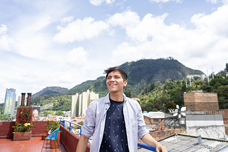 年轻男子在哥伦比亚波哥大的坎德拉里亚历史区屋顶欣赏街道风景。图片素材