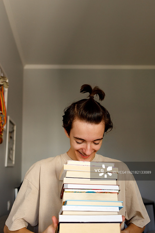 帅气的少年手握叠好的书籍，准备返校。图片素材