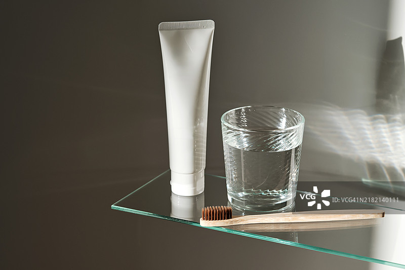 浴室玻璃架上的水杯、牙刷和牙膏图片素材