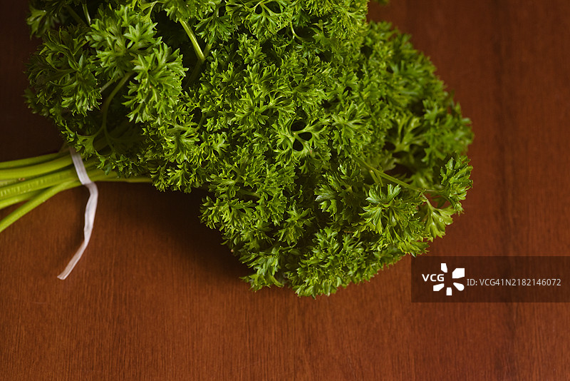 一束新鲜的香 parsley 在古朴的木砧板上图片素材