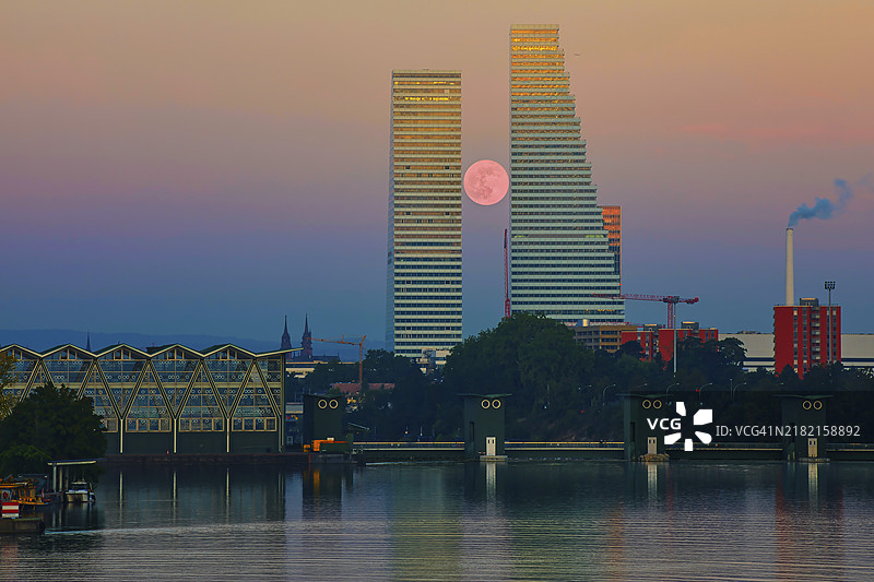 两座摩天大楼在满月和日落的映衬下，倒映在宁静的水面上，罗氏大厦，霍夫曼-拉罗氏，瑞士最高建筑，巴塞尔，巴塞尔城市州，瑞士，欧洲图片素材