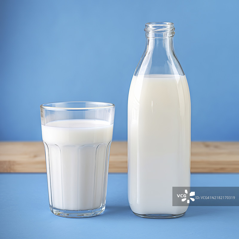 一个装满牛奶的透明玻璃杯和旁边的透明瓶子图片素材