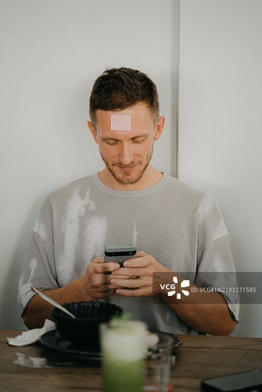 朋友们聚在一起吃饭并玩“我是谁”的游戏图片素材