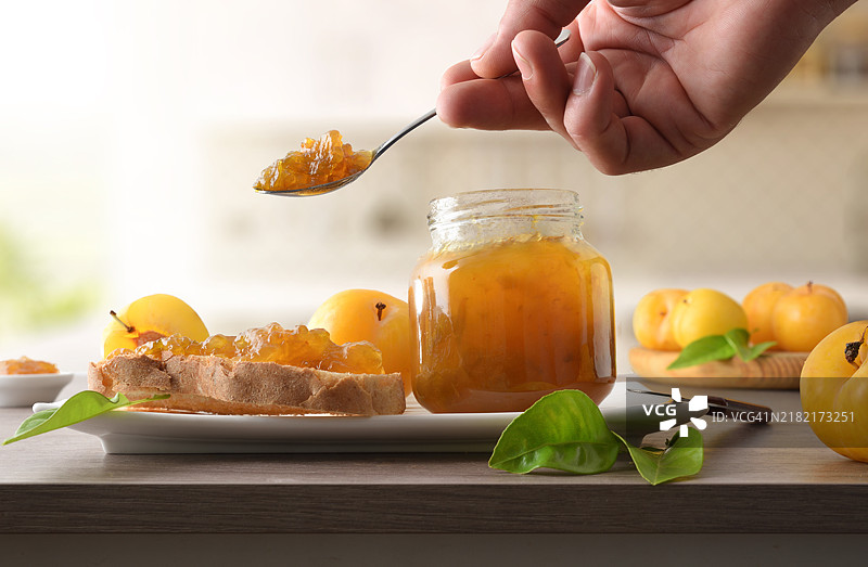 在厨房台面上准备涂梅子果酱的吐司图片素材