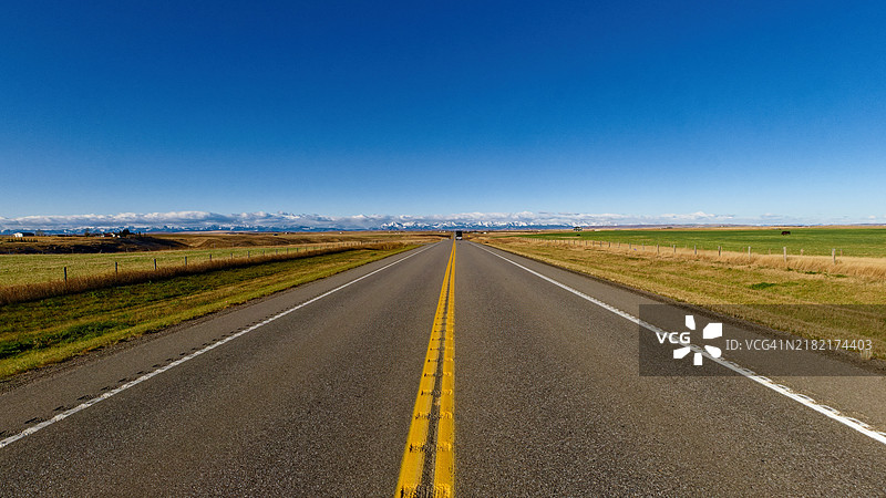 空旷的道路穿过田野，映衬着蓝天图片素材