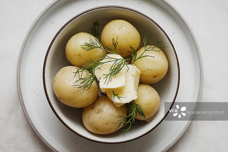 一盘早熟土豆、黄油和新鲜莳萝的菜肴照片图片素材