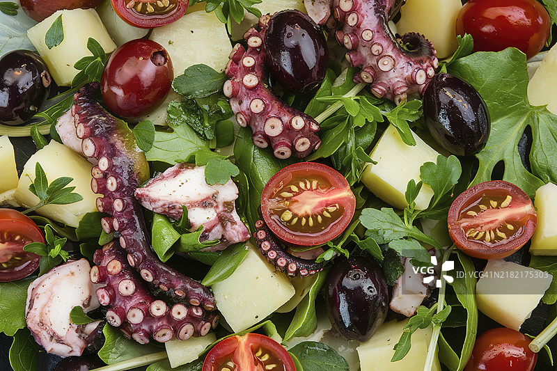 一盘特写的沙拉，里面有橄榄、香草、切片樱桃番茄、 diced 土豆和章鱼触手块。图片素材