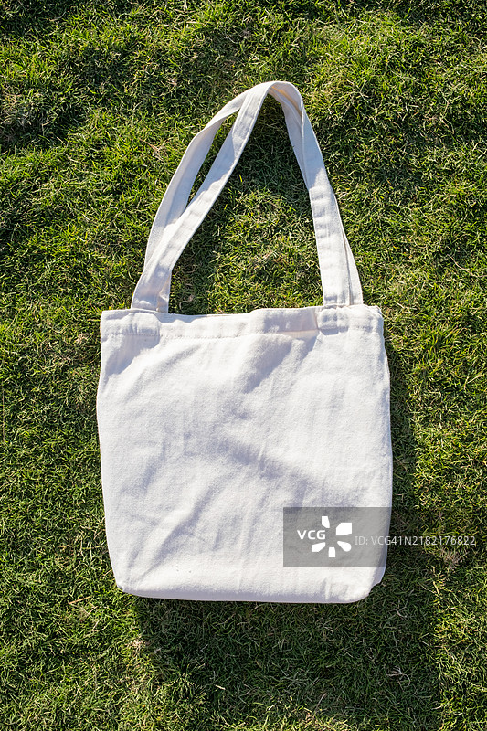 绿色草地背景上的购物手袋样机图片素材