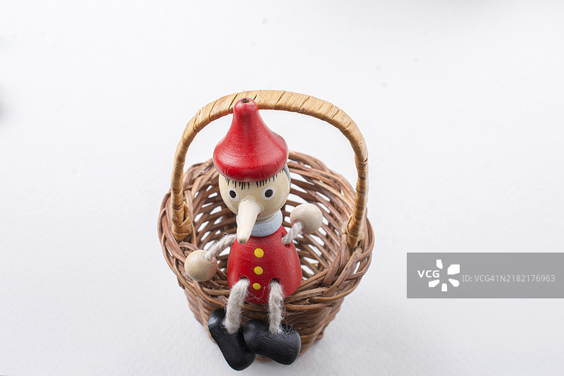 皮诺丘玩具小雕像坐在草篮里图片素材