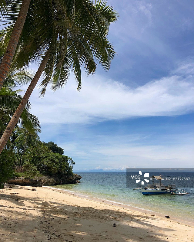 菲律宾的宁静热带海滩，船只与棕榈树图片素材