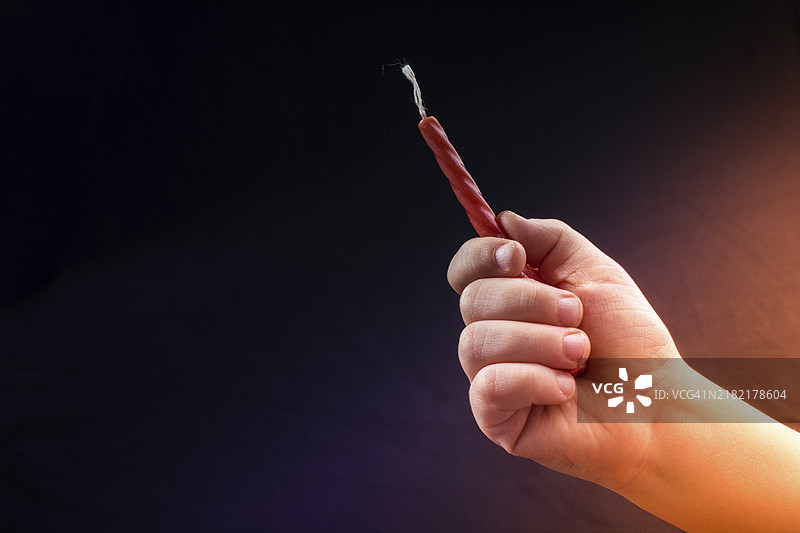 黑色背景下手中握着的彩色蜡烛图片素材